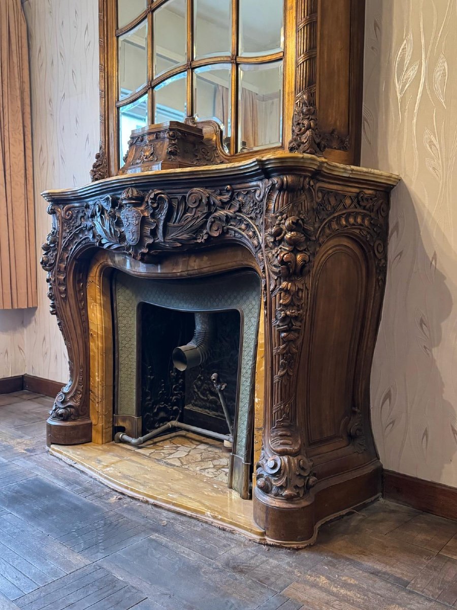 Impressive fireplace and its richly carved wooden trumeau highlighted with yellow Siena marble, circa 1900