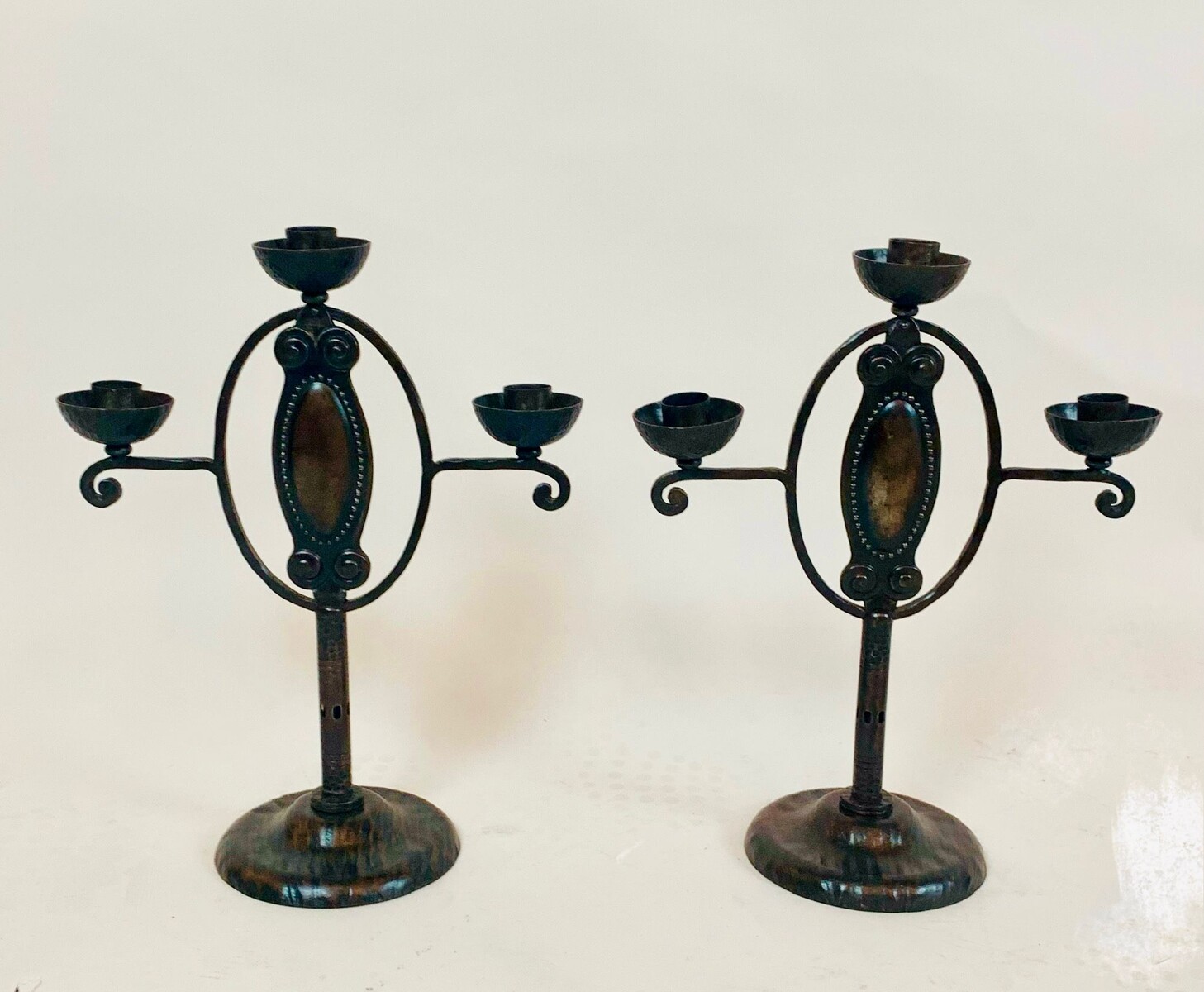 Pair of arts and crafts candlesticks in wrought and hammered iron